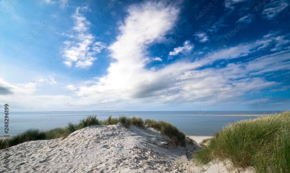 Dune beach on the North Sea island Langeoog in Germany with clouds on a beautiful summer day, holidays in Europe Dune beach on the North Sea island Langeoog in Germany with clouds on a beautiful summer day, holidays in Europe
