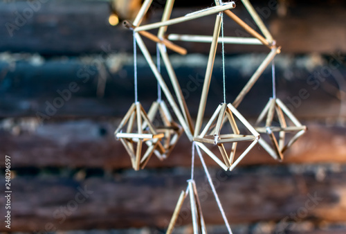 Latvian Puzurs hanging in the dark log hut. Puzurs is traditional Latvian room decoration made of reeds or straws. It is solstice symbol similar to Finnish Himmeli and Lithuanian Siaudinis Sodas.
