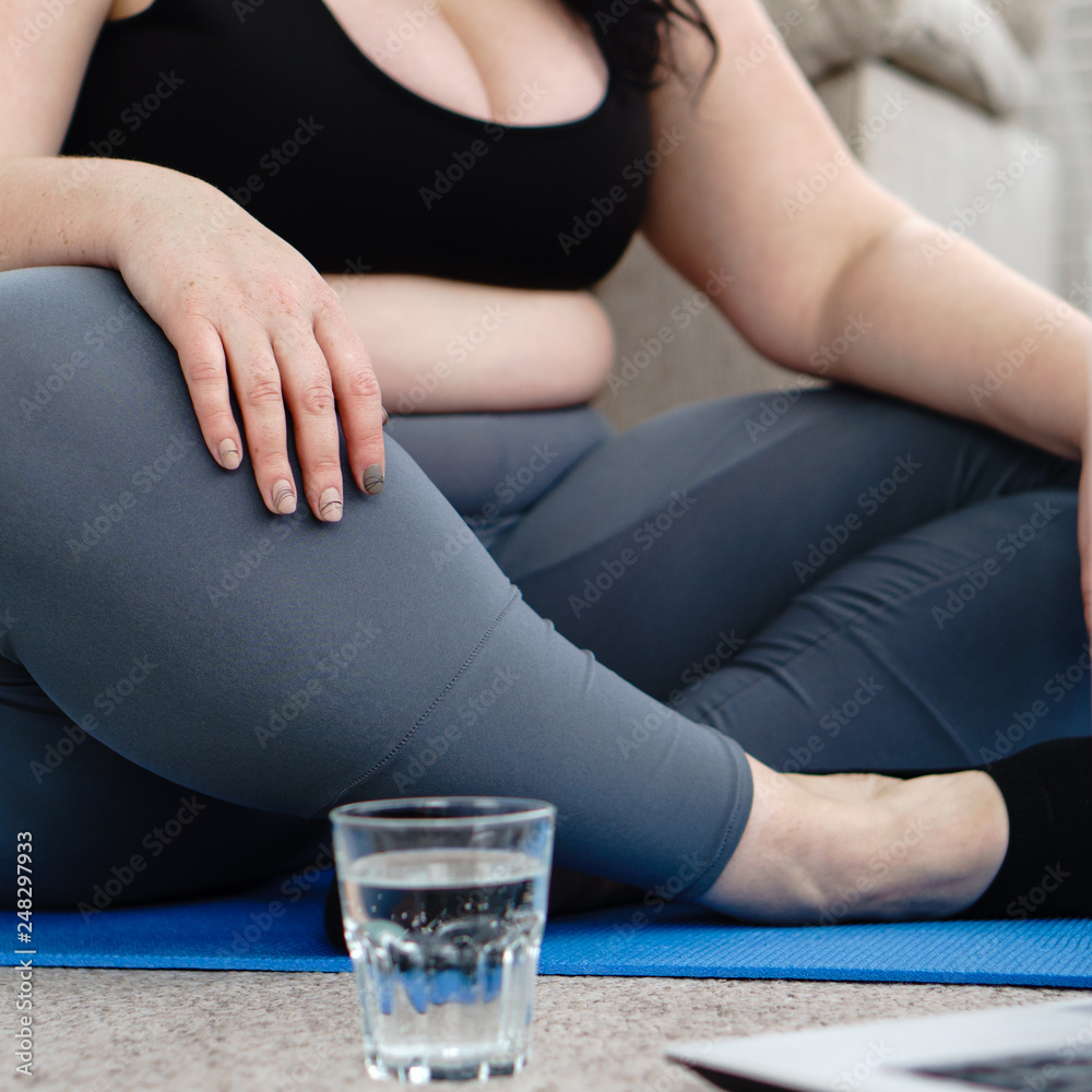 sport, home training, online fitness class, relaxation, balance, flexibility. overweight woman rest and drink water after yoga workout at home. weight loss, healthy lifestyle
