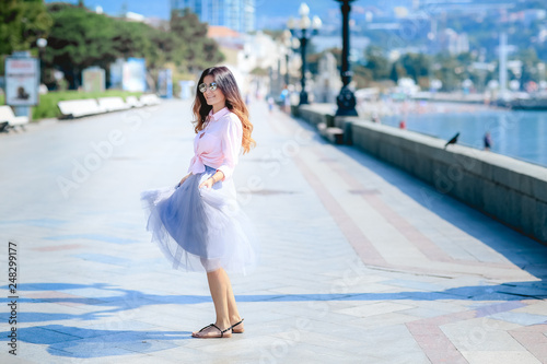 Girl walking along the seafront in dress in hot summer day