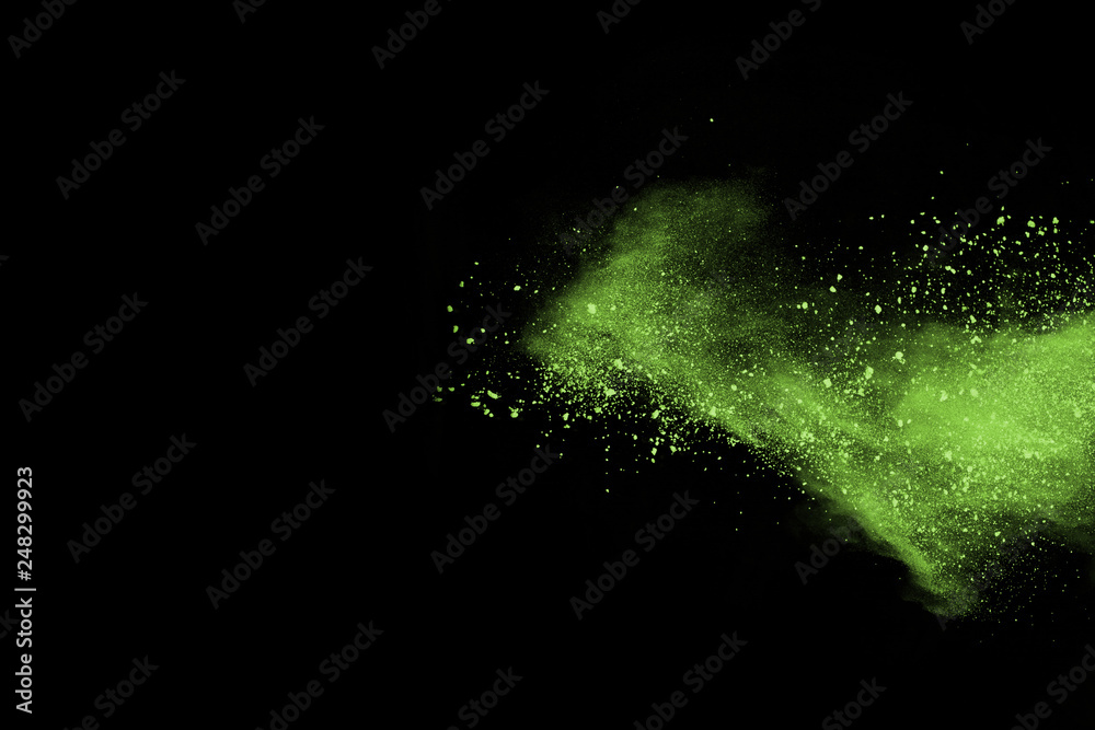 Fototapeta premium The movement of abstract dust explosion frozen green on black background. Stop the movement of powdered green on black background. Explosive powder green on black background.