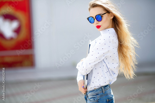 Close up fashion portrait of attractive woman in jeans with long hair.Girl in jeans suit.Charming lady with new denim outfit. Happy young woman in city street