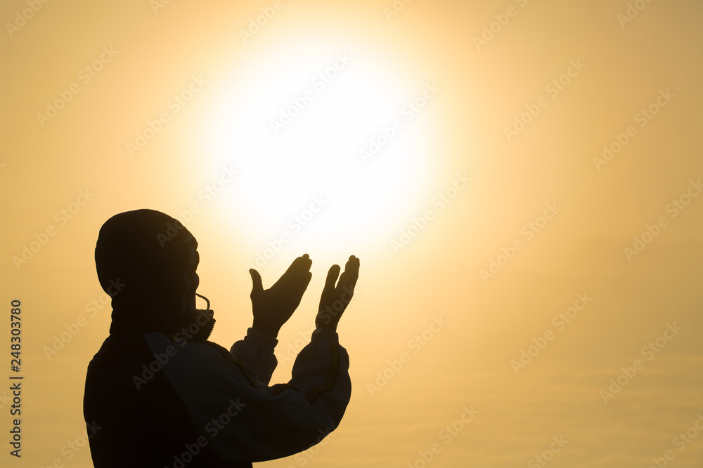 Silhouette of young  man hands open palm up worship and praying to god  at sunrise, Christian Religion concept background.