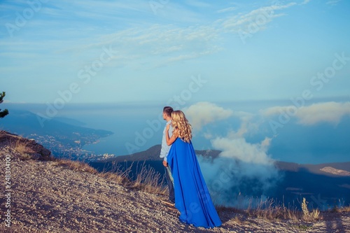 Beautiful couple of newlywed hugging at wedding day on cliff with ocean view. Stylish bride and elegant groom look at each other with love. Concept honeymoon  family  marriage  just married