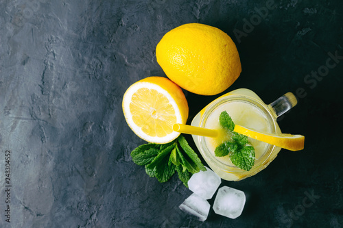 Refreshing lemonade drink with lemon slice and mint in the jar on dark background, top view