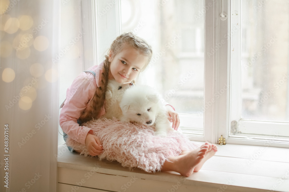 The girl with a pillow and white puppy in her arms.