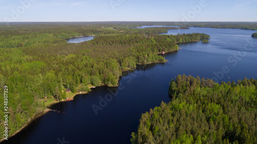 Summer panorama of beautiful lake and forest. Traditional Finnish huts in forest.