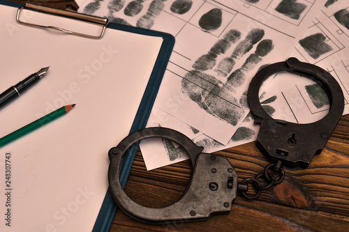 fingerprints, handcuffs on wooden table background. arrest, detention of the criminal, prison. photo
