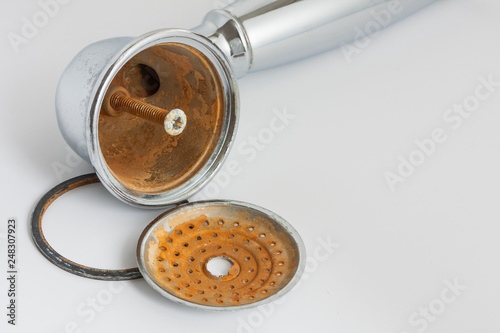 Broken rust-eaten shower head with limescale and rust stains on it