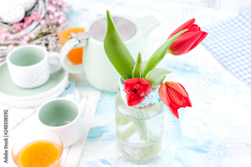 Bouquet of fresh red tulips in a vase on a white table. Spring Easter breakfast with flowers and free space for text.