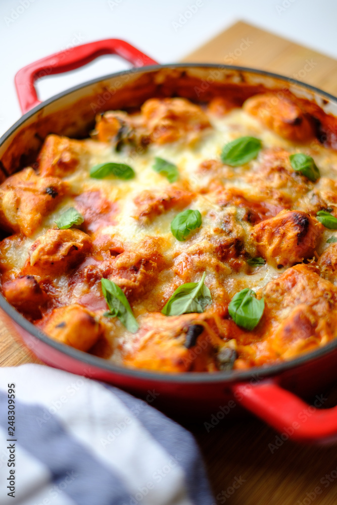 Homemade gnocchi baked in tomato sauce with spinach, toasted cheese on and fresh basil on top.