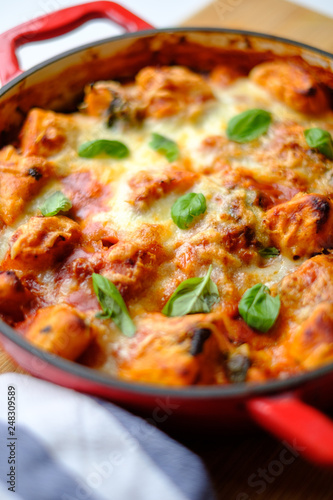 Homemade gnocchi baked in tomato sauce with spinach, toasted cheese on and fresh basil on top.