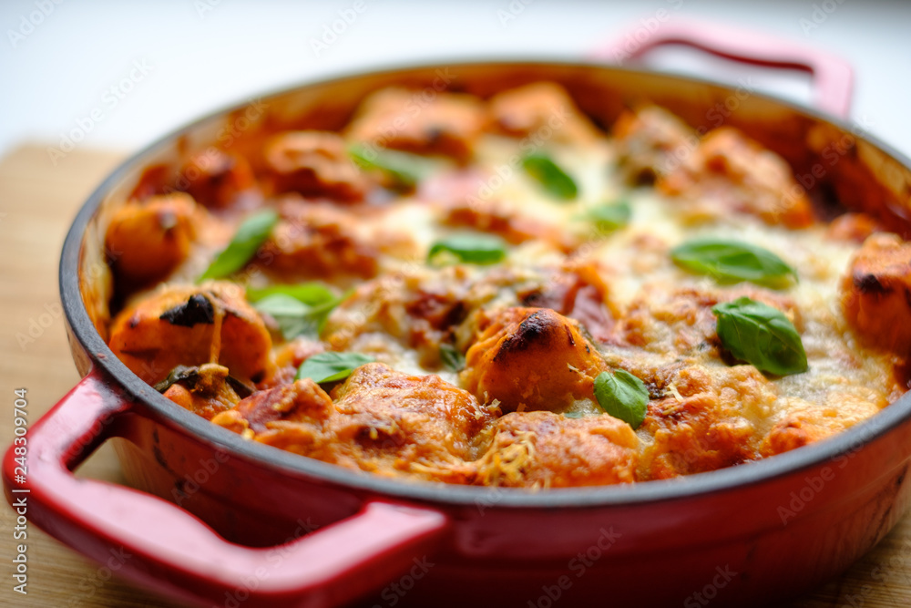 Homemade gnocchi baked in tomato sauce with spinach, toasted cheese on and fresh basil on top.