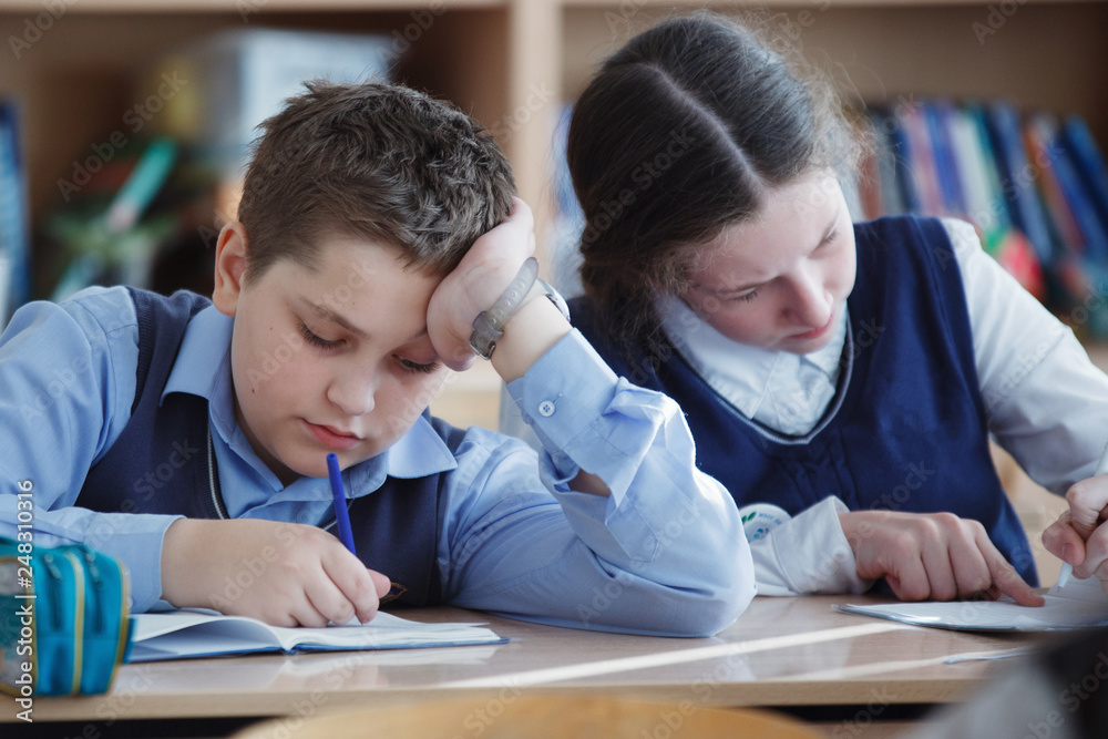 A young schoolboy sitting at a desk in a school class. A young schoolboy sitting at a desk in a school class.