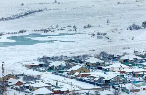 Winter landscape with a village on the lake. The village, houses in the winter on the shore of the reservoir.