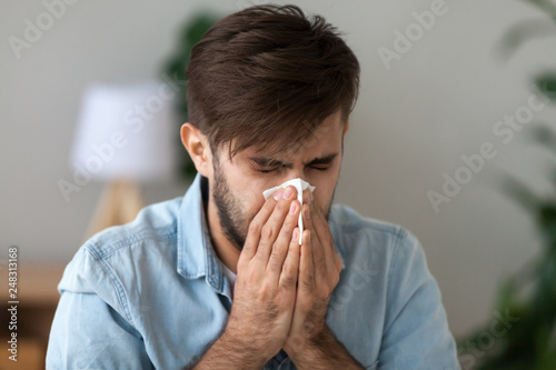 Sick man got flu allergy sneezing in handkerchief blowing nose