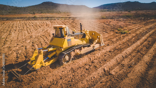 Aerial image of a bulldozer pushing and ripping ground on an agricultural piece of land