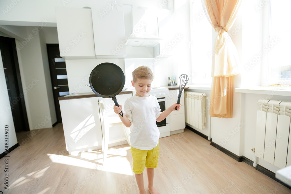 funny European little boy chef dancing,Happy weekend, boy wants to make pancakes, but the frying pan are too gay, he decided to have fun holding wooden spoons in his hands, having fun while cooking