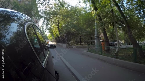The car moves along the city street on sunny summer day. Side view of the car body.