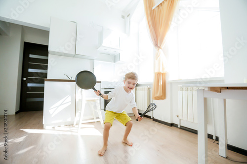 funny European little boy chef dancing,Happy weekend, boy wants to make pancakes, but the frying pan are too gay, he decided to have fun holding wooden spoons in his hands, having fun while cooking