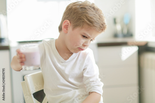 Kid or blonde happy boy eating at table. Childhood and happiness, independence. Breakfast, morning, family. Small boy child eat banana and drink milk. Healthy food and vitamin. dieting, vegetarian