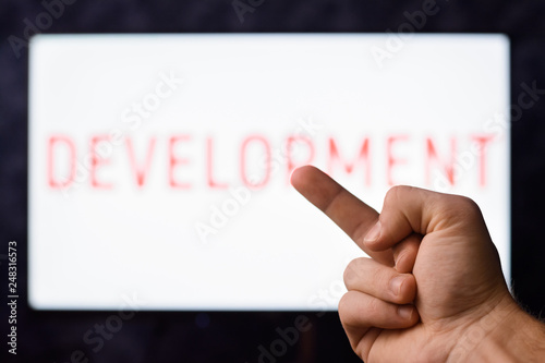 Man showing middle finger to screen with inscription DEVELOPMENT. Symbol of degradation.