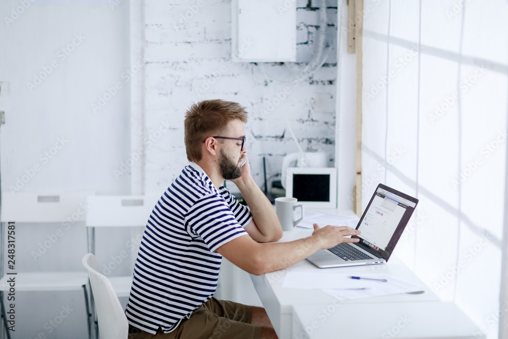 Freelancer man at work in office and looking at open laptop workstation. Freelancer man at work in office and looking at open laptop workstation.