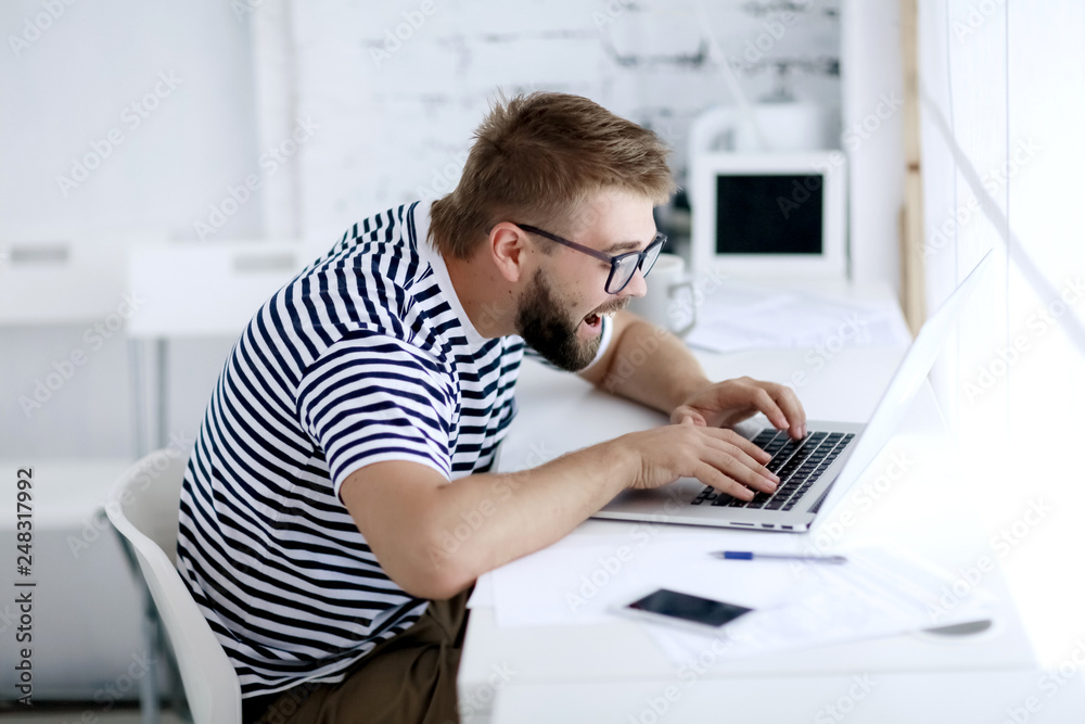 impulsive man with open mouth looks into the laptop in the office. impulsive man with open mouth looks into the laptop in the office.