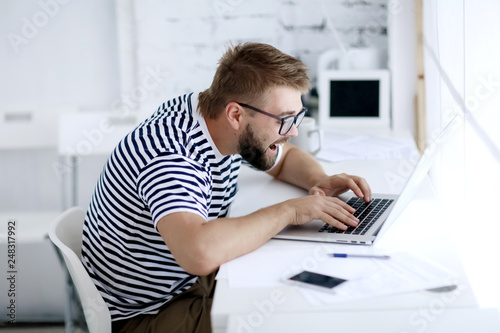 impulsive man with open mouth looks into the laptop in the office.
