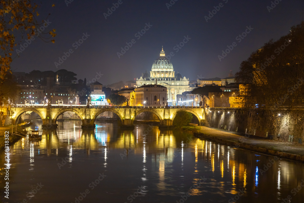 Rome night skyline with Vatican St Peter Basilica and St Angelo Bridge crossing Tiber River in the city center of Rome, Italy. It is historic landmark of the Ancient Rome and travel destination.