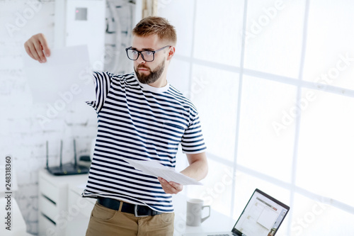 Successful businessman. Office worker. Portrait of bearded businessman. Serious businessman. Man standing at table and holds laptop. Handsome bearded office worker.