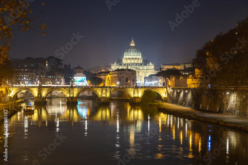 Rome night skyline with Vatican St Peter Basilica and St Angelo Bridge crossing Tiber River in the city center of Rome, Italy. It is historic landmark of the Ancient Rome and travel destination.