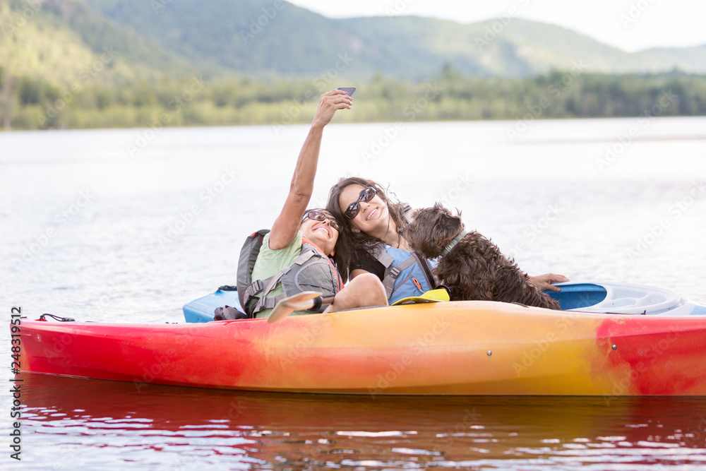 Mother and Daughter Streaming video, facetime, or Taking Selfie with Dog in Kayak while on Vacation