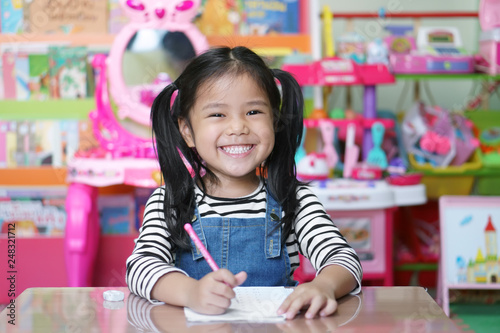 asian child cute or kid girl smiling diligent review and enjoy doing mathematics homework or happy learning and training writing on white paper or book at nursery preschool or home and kindergarten photo