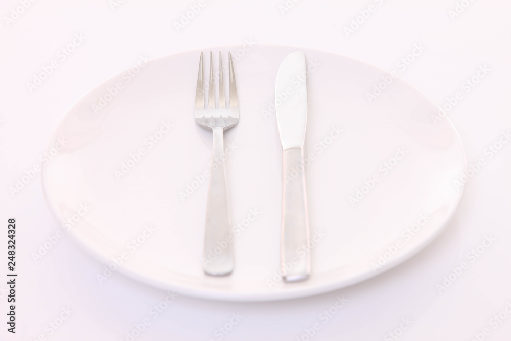 白いテーブルに置かれた白い皿とカトラリーによる食事終了の合図