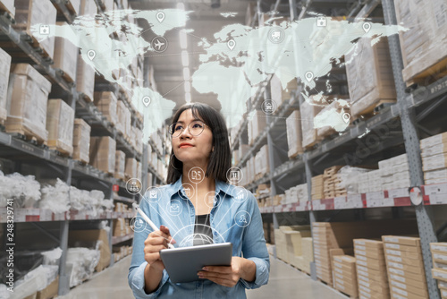 Portrait of happy young attractive asian entrepreneur woman looking at inventory in warehouse using smart tablet in management technology,  interconnected industry, asian small business sme concept. photo