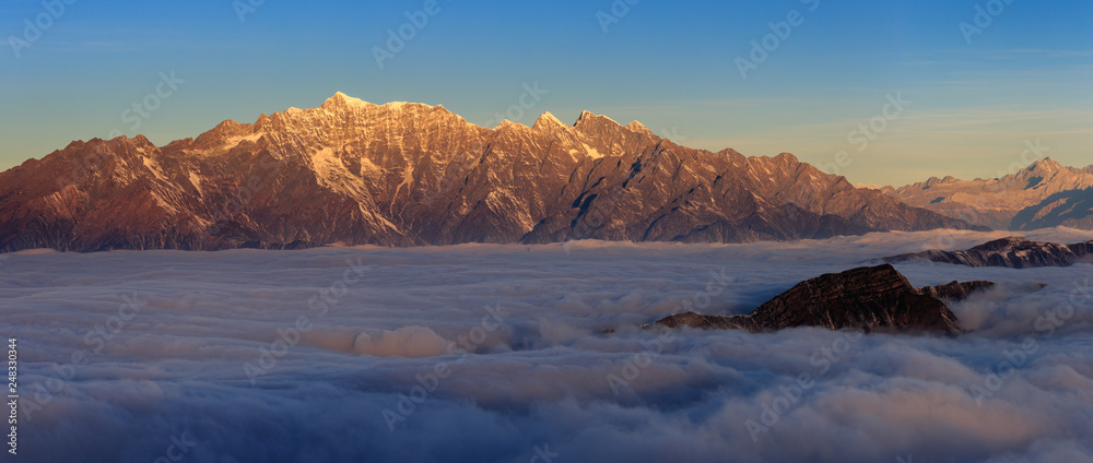 Mountains floating above the sea of clouds, appearing like islands an ocean - Niubeishan Landscape, Cattle Back Mountain, Sichuan Province China. Snow mountains, fluffy clouds, panoramic scenery