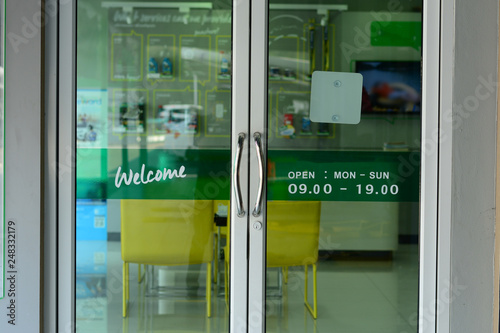 the glasses door with welcome letters and open time on green label at car repair shop