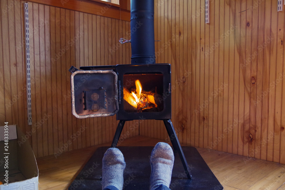 Man's feet in Wool socks relaxing in front of wood stove burning in a cozy tiny  house cabin Stock Photo | Adobe Stock