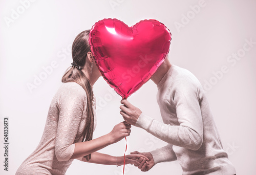 Valentine's day. Happy joyful couple holding heart shaped air balloon and kissing. Love. Happy Valentine's Day celebrating