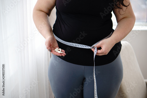 weight loss, medical therapy, diabetes prevention. Fat obese woman with pills and measure tape