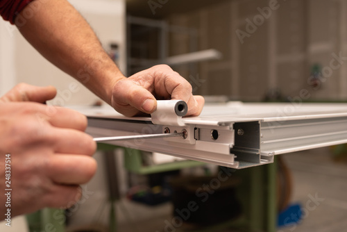 close up of worker hands assembling a hinge on aluminium door