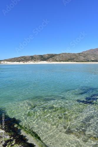 Beach with mountain, lake, white sand and clear water with turquoise colour. Playa de Carnota, Coruña Province, Spain.