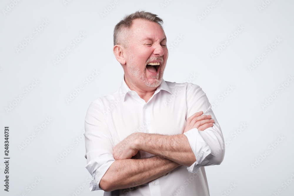 Smiling elderly man in white shirt standing at studio. Smiling elderly man in white shirt standing at studio.