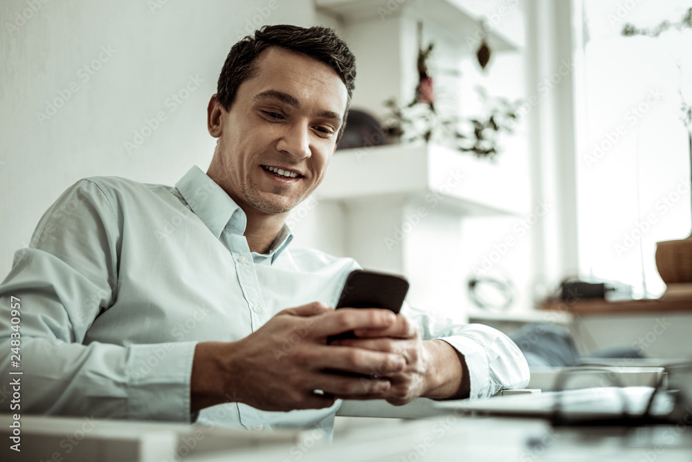 Pleased male person typing message to his partner Pleased male person typing message to his partner