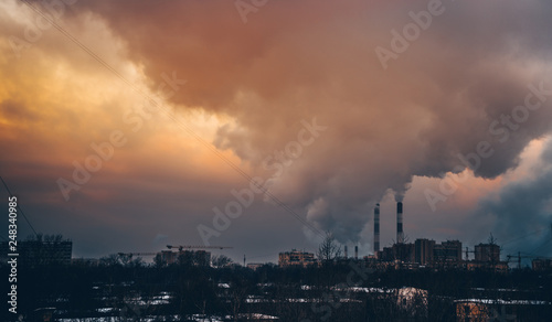 The smoking chimneys of the plant create smoog in the boring atmosphere at sunset.