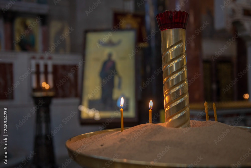 Candles in Russian orthodox cathedral with icons on background