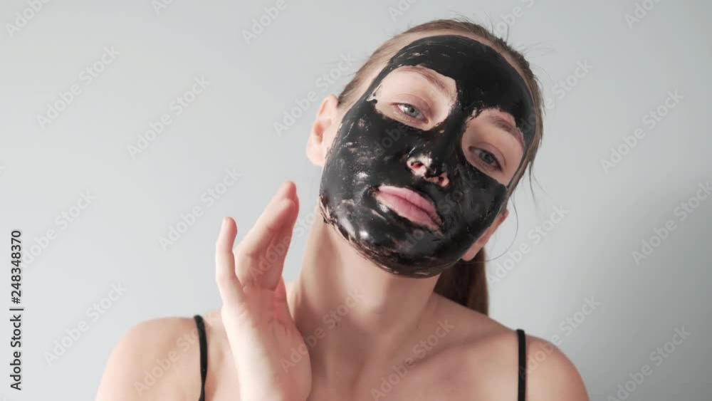 A beautiful young woman put a black mask film on her face. She checks with her fingertips - the mask is choked or not. The girl smiles and starts to pull the film off the edge of her face. Close-up. A beautiful young woman put a black mask film on her face. She checks with her fingertips - the mask is choked or not. The girl smiles and starts to pull the film off the edge of her face. Close-up.