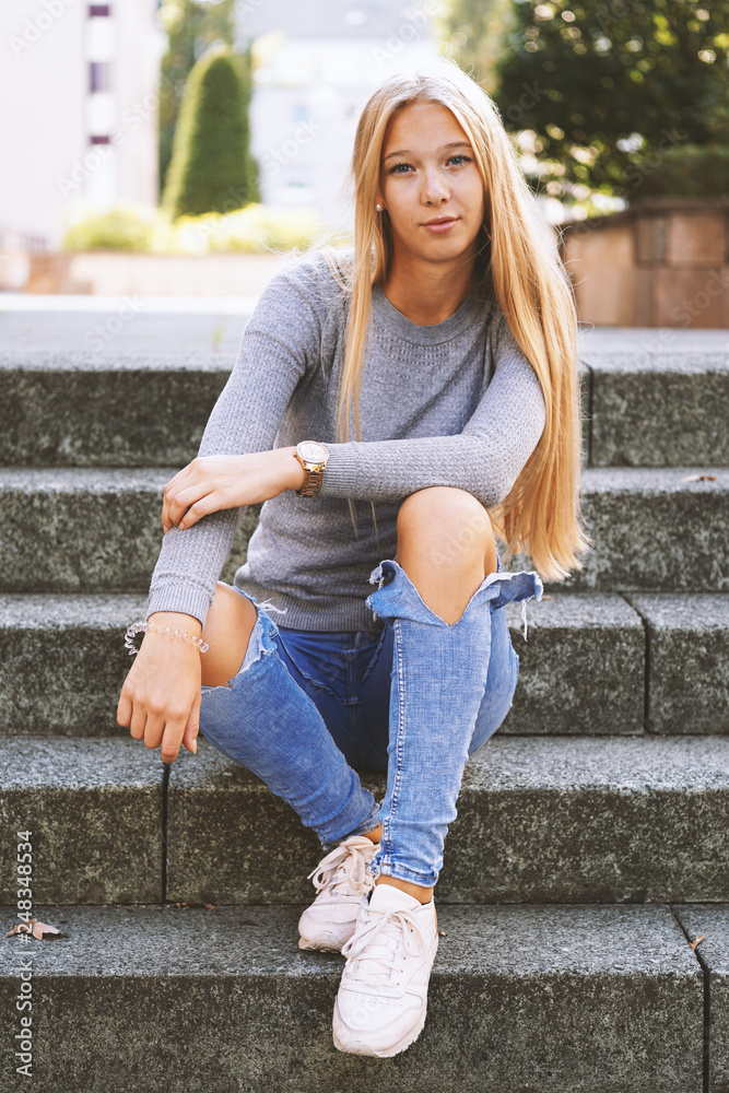 tolv Grønthandler Ruin teenage girl with long blond hair and distressed jeans sitting on steps  outside - urban lifestyle or street fashion concept Stock-foto | Adobe Stock