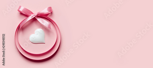 Valentine's Day greeting card. A circle of satin ribbons with a bow, inside of which is a heart on a bright background.